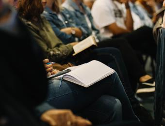 People seated holding books and pens