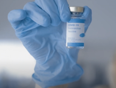 A scientist holds up a vial of COVID-19 vaccine
